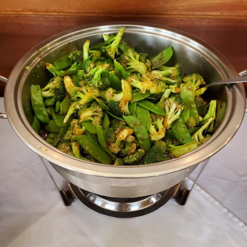 Steamed broccoli and snap peas in a silver chafing dish, ready to be served at China 10.