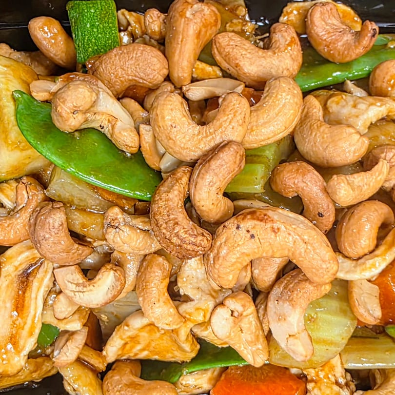 Close-up of China 10's cashew chicken with snow peas, zucchini, and bell peppers in sauce.